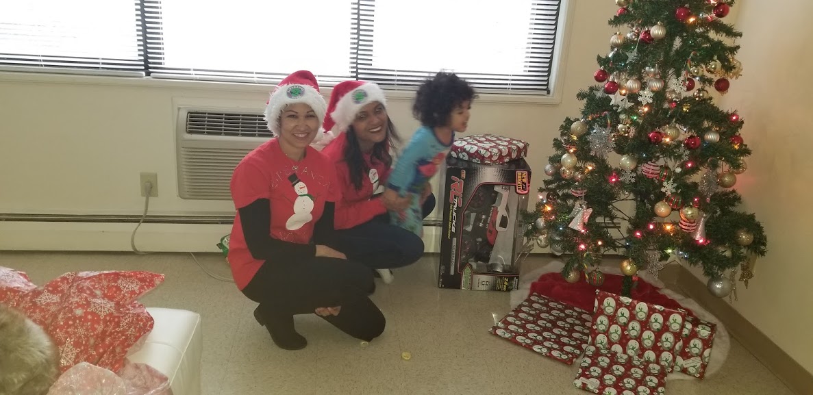 Two of our female staff wearing Santa hats and a child trying to run
