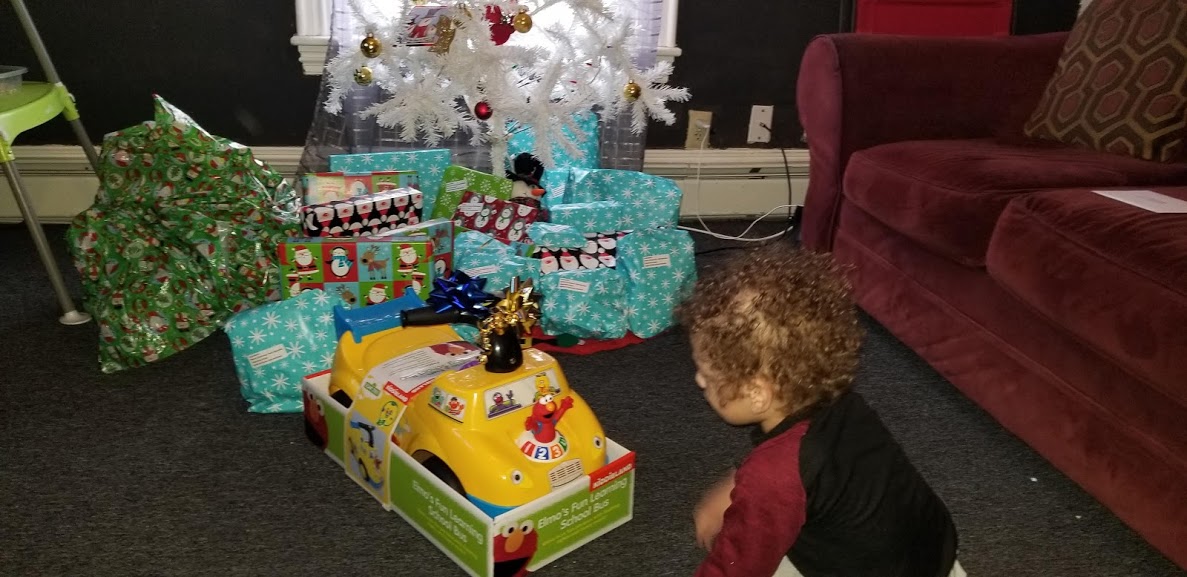 A little boy sitting on the floor in front of the presents
