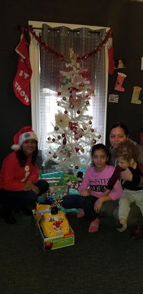 Our female staff together with a woman and her two children with a toy car and a white Christmas tree