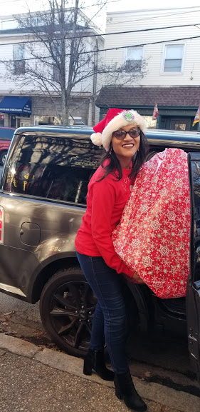 Our female staff carrying a big red Christmas gift from a car