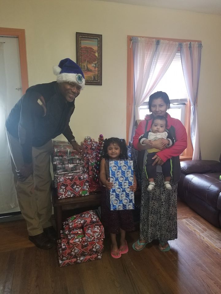 A male staff and a mother with her two children posing with their Christmas gift donations