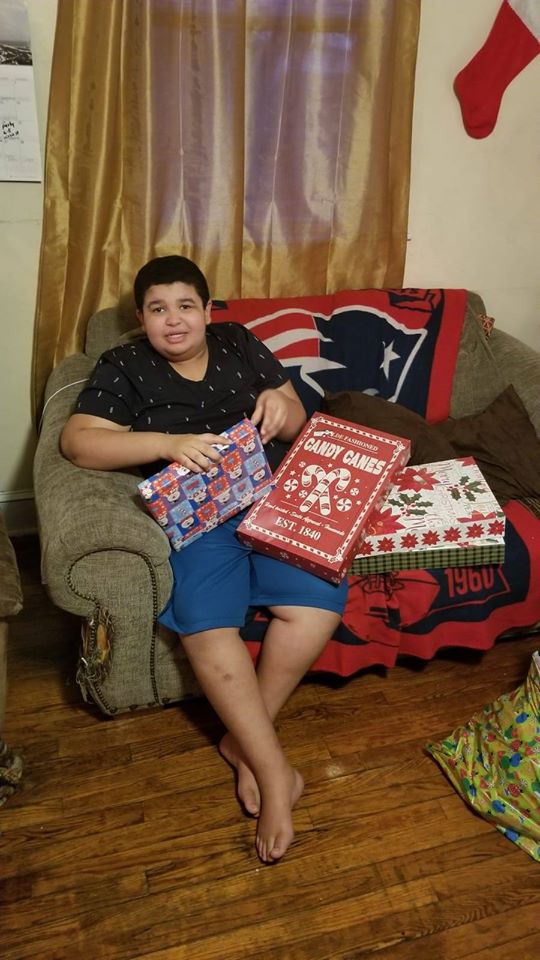 A boy sitting on the couch and holding gifts