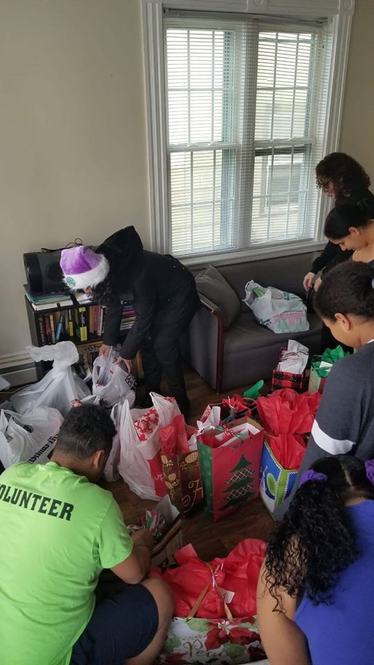 A group of people packing the already wrapped gifts in a living room