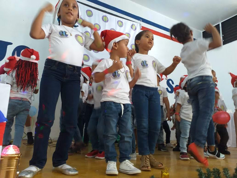 Little children wearing Santa hats and standing on the stage