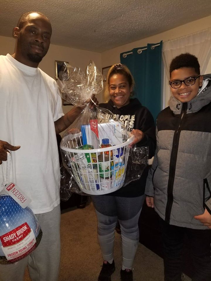 A tall man holding a turkey bag, a woman carrying a basket of groceries, and a boy