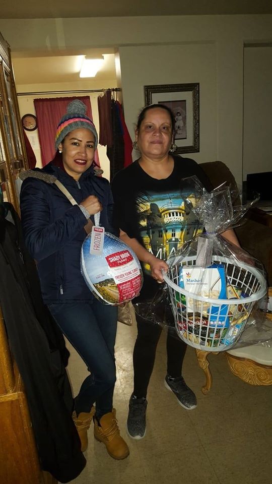 Our female staff holding a bag of turkey and another woman holding a basket of groceries