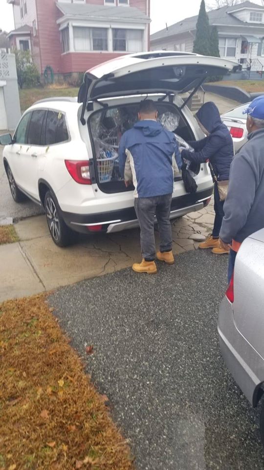 Two people wearing jacket getting baskets from a car trunk