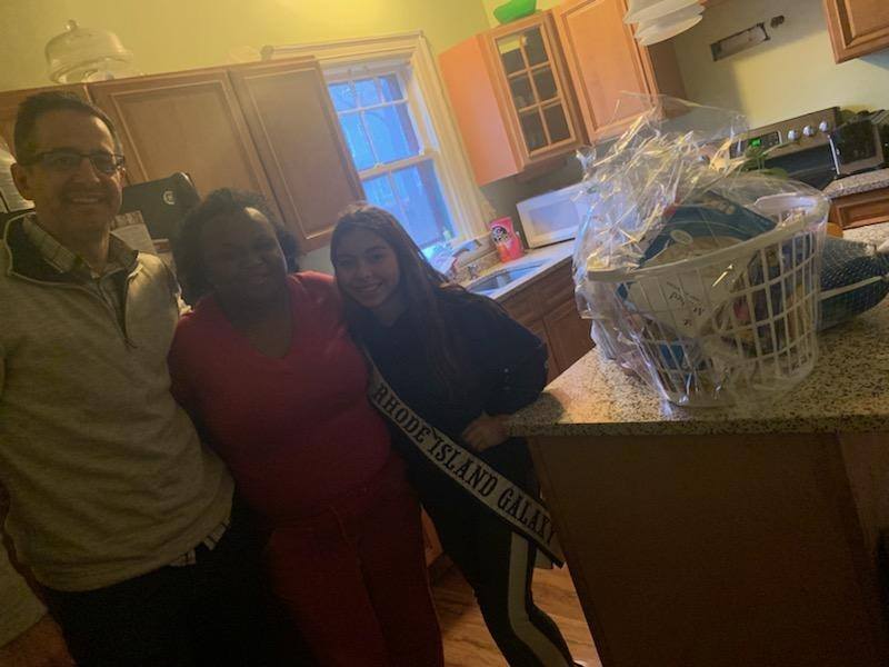 Ms. Rhode Island Galaxy together with a man and a woman and a basket of food on the kitchen counter
