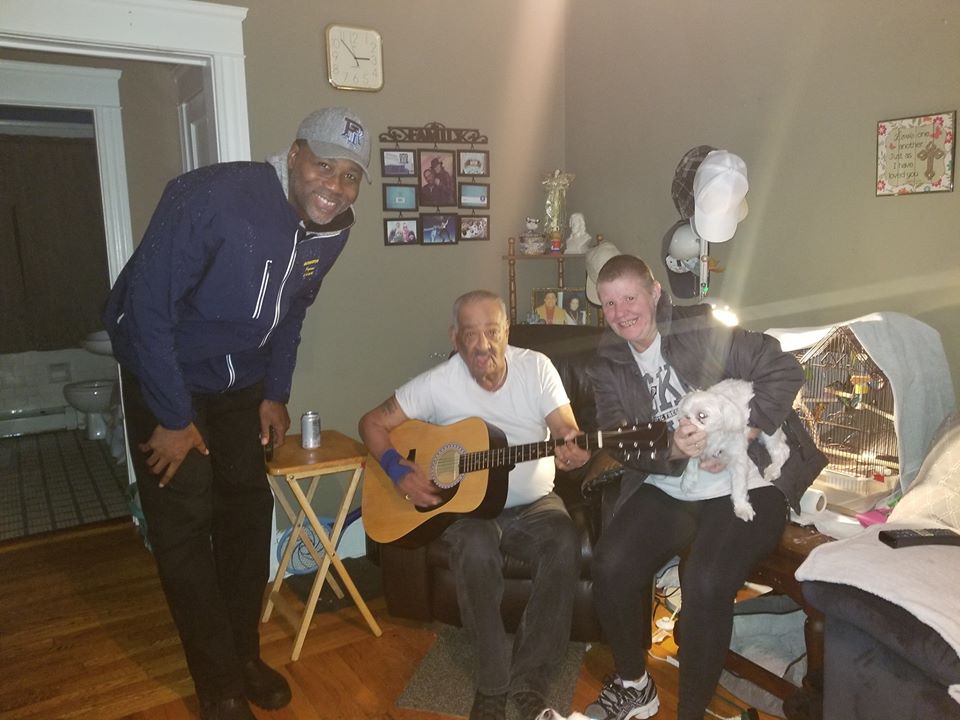 Two of our staff together with an elderly man holding a guitar