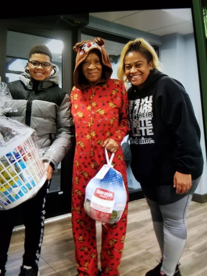 Our female staff together with a woman in a onesie holding a bag of turkey and a boy carrying a basket of groceries