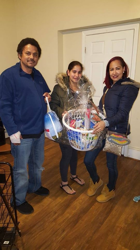 A man holding a bag of turkey and two women holding a basket of groceries