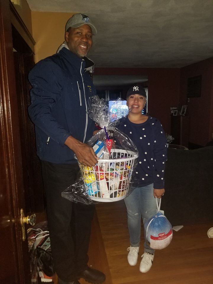 A tall man wearing a cap and holding a basket of groceries and a woman holding a bag of turkey