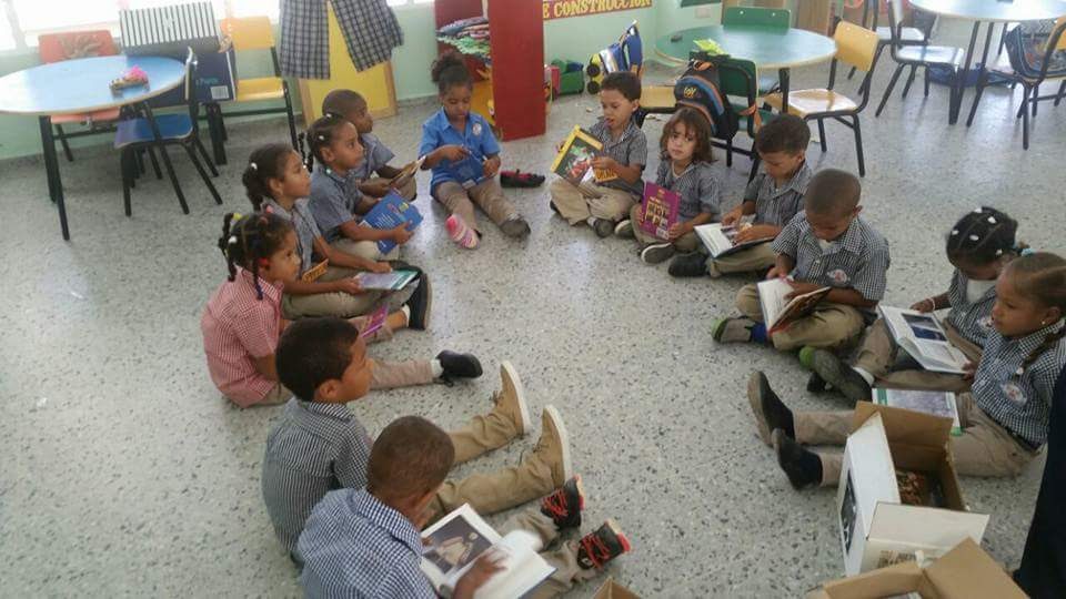 Young children in school uniform forming a circle and holding their books
