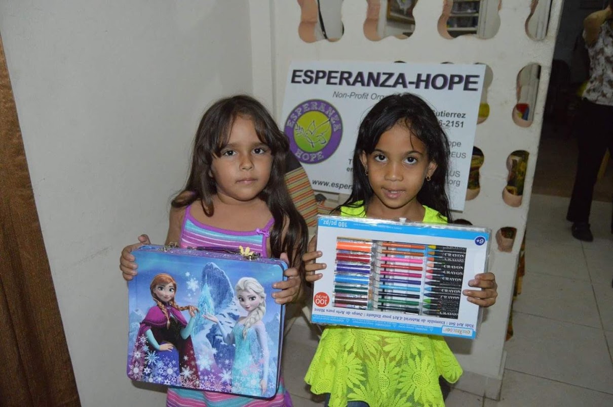 Two little girls, one holding a Frozen toy box and another a big crayon set