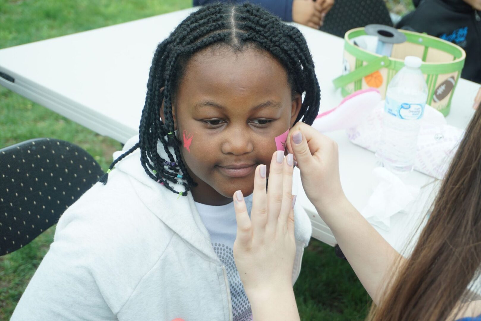 A girl with braided hair getting face painted