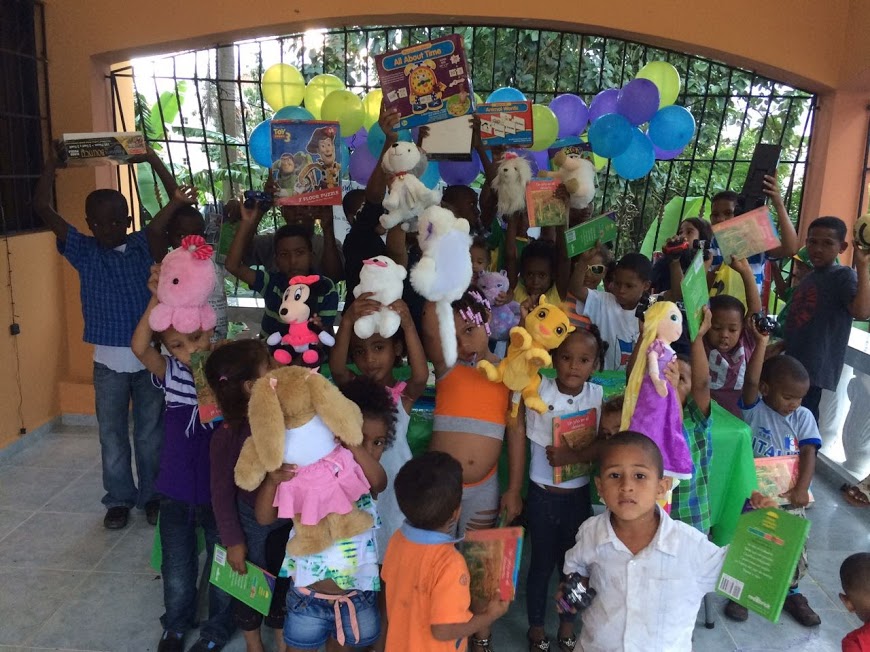 Children gathered and holding their gifts up in the rooftop area with the window