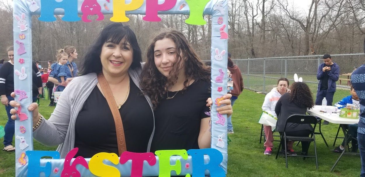 Two women posing black tops posing with the Happy Easter frame, close-up