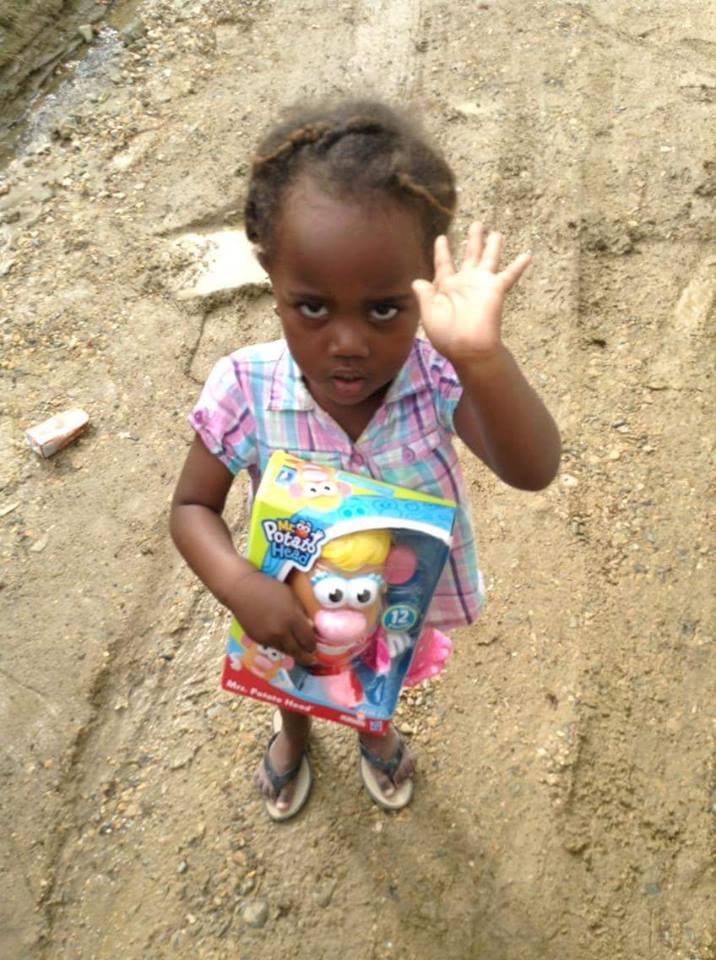 A little girl holding a box of Mrs. Potato Head toy