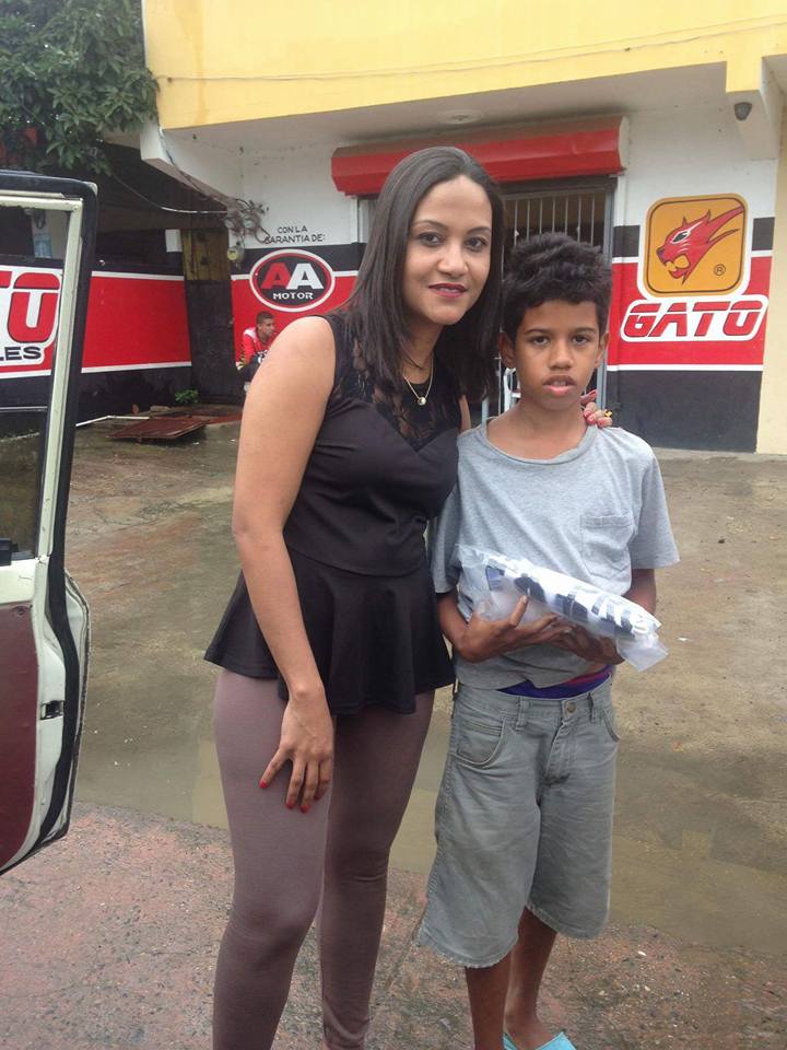A boy receiving a pack of clothes in front of an auto shop