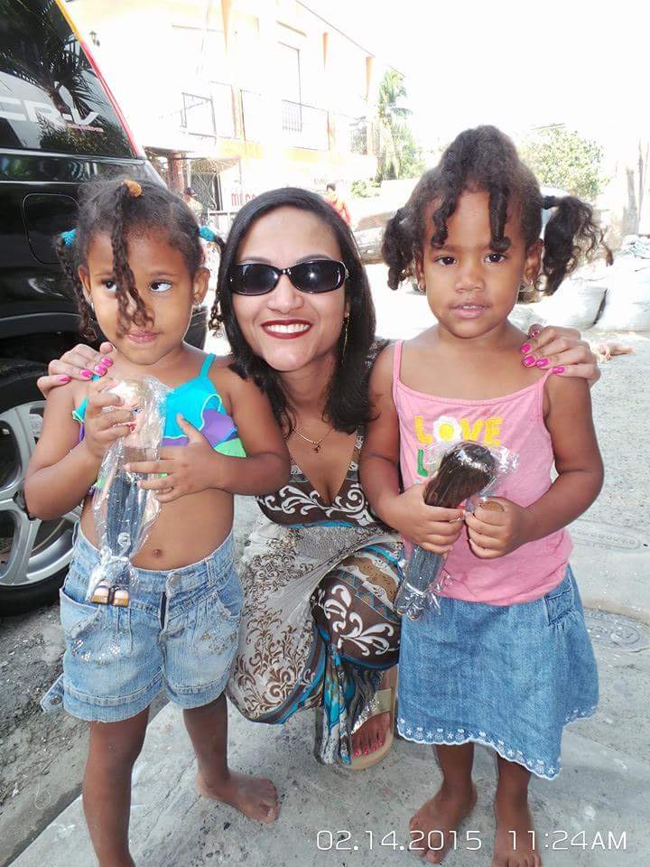 A woman and two little girls holding dolls on the road (version 2)