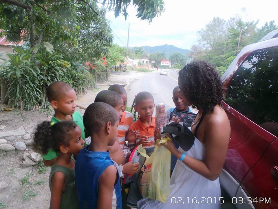 A woman holding a plastic bag and giving toys to a group of children