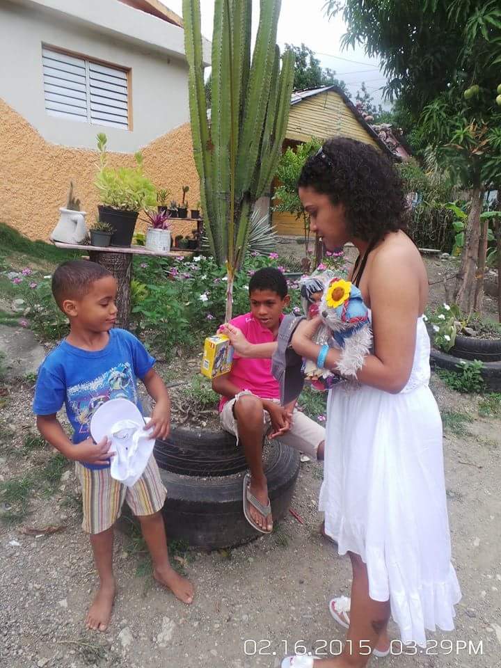A woman giving toys to two boys near a tire plant box