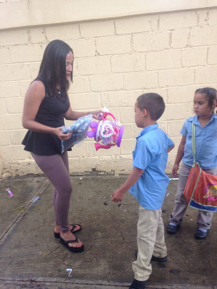 Our staff giving toys to a boy and girl in a blue school uniform