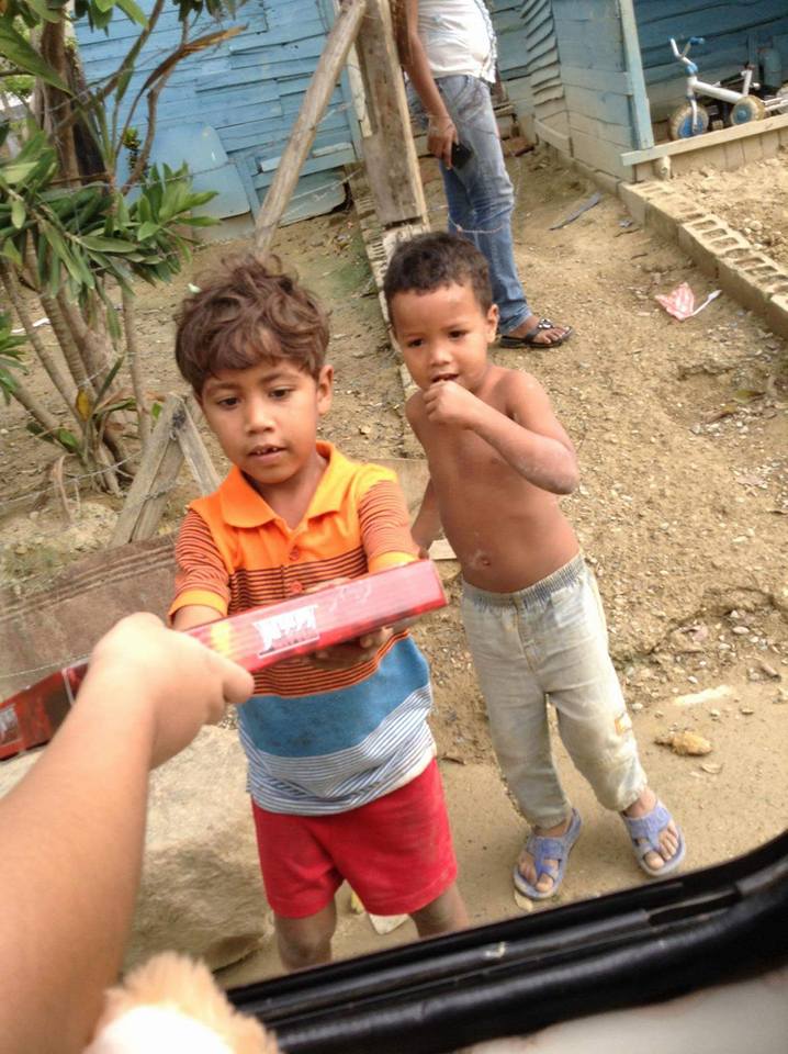 A boy receiving a box of toy from a person inside the car
