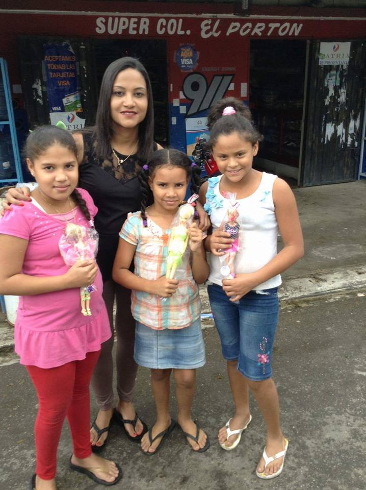A staff and three girls holding dolls in front of a shop