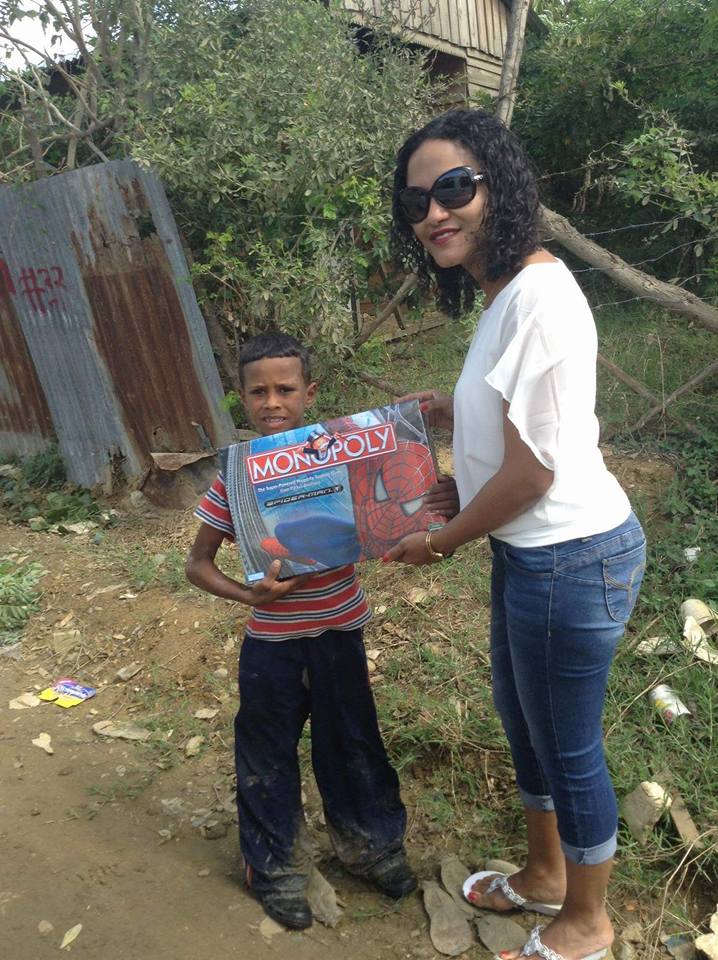 A staff giving a Spiderman monopoly box to a boy