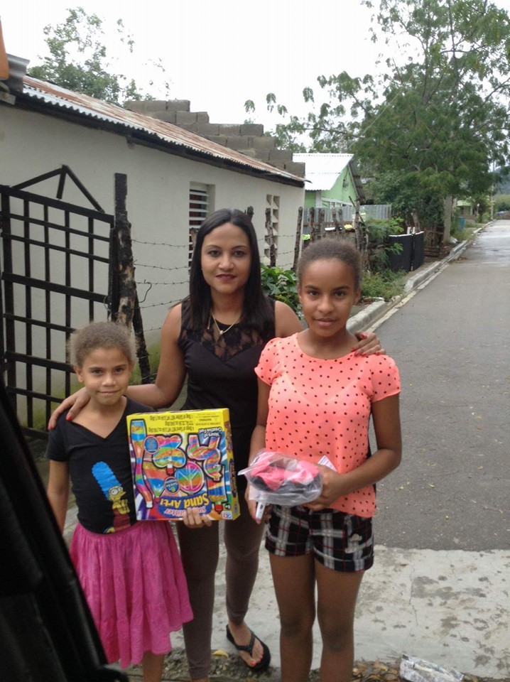 Our staff and two girls holding a toy and a pack of clothes