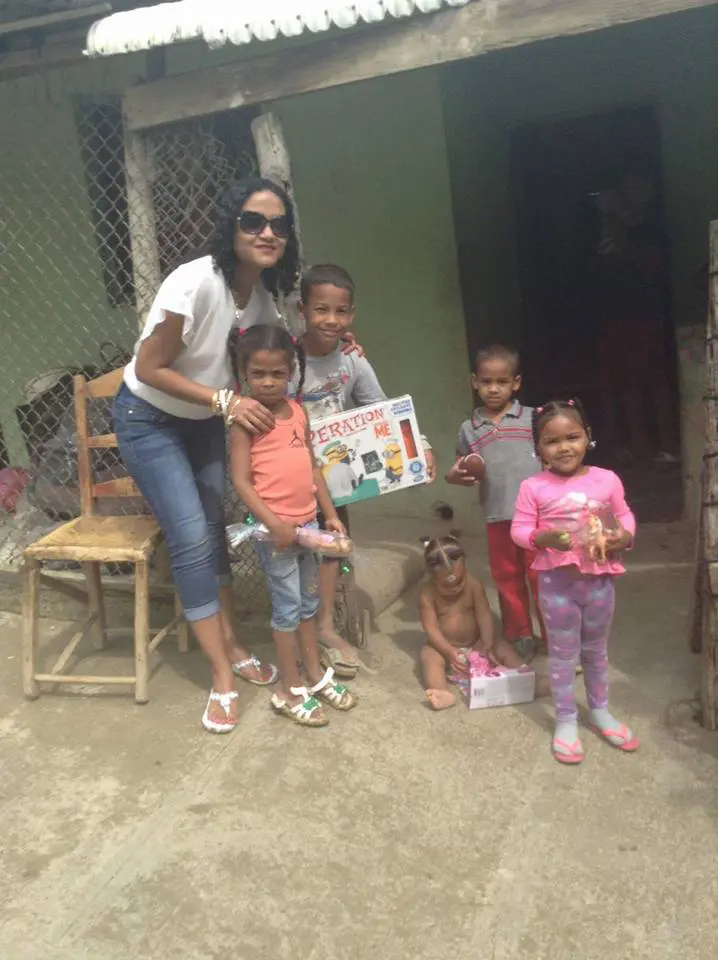 A staff and five children holding toys outside a house