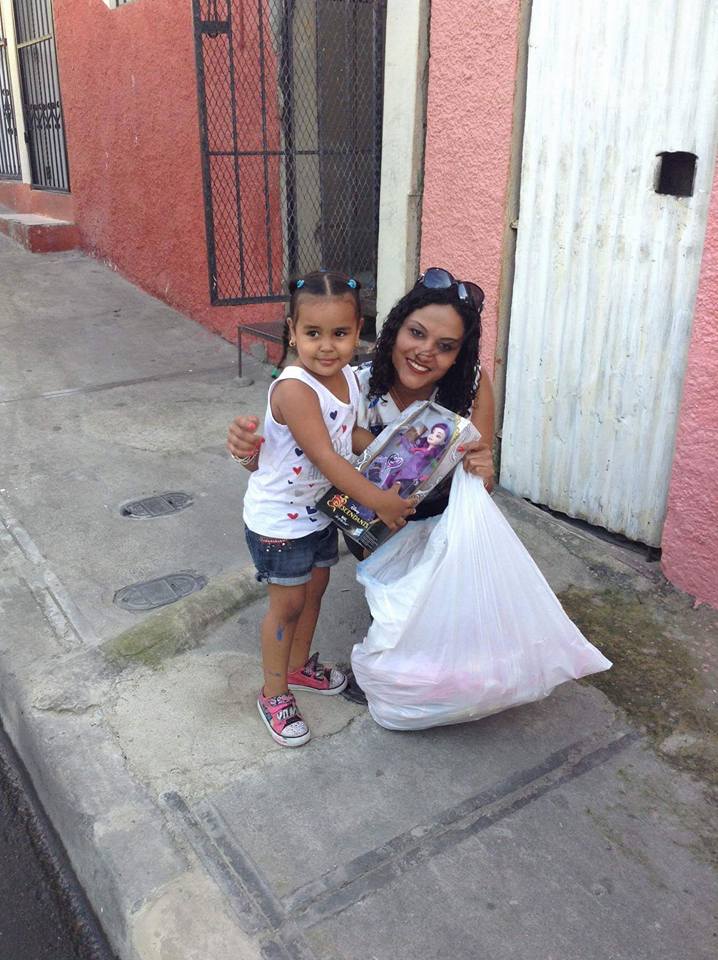 A woman with a big white plastic bag and a girl holding a doll, smiling (version 2)