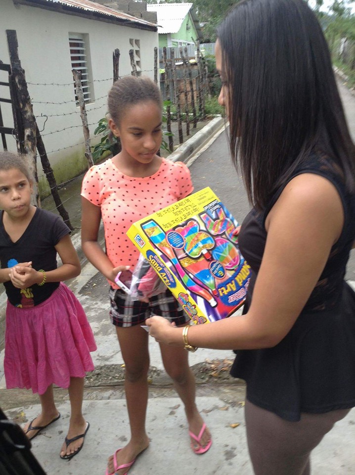 Two girls receiving a pack of clothes and a box of toy on the road