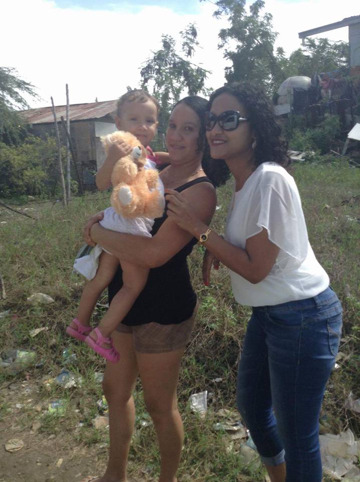 A staff and a woman carrying a baby who is holding a yellow teddy bear