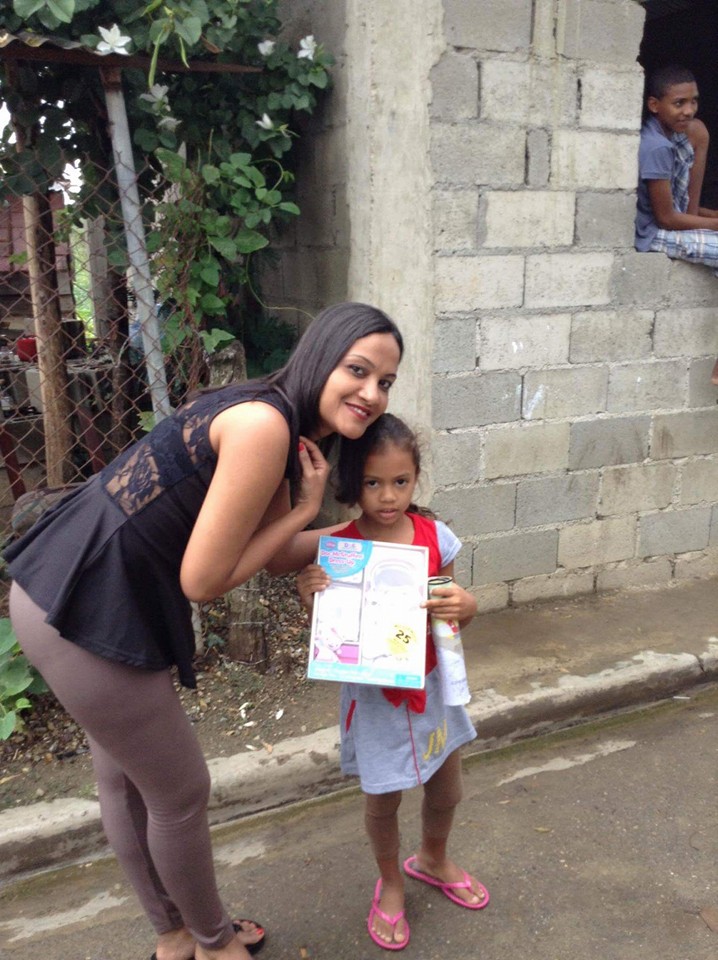A girl receiving a book and a toy on the road