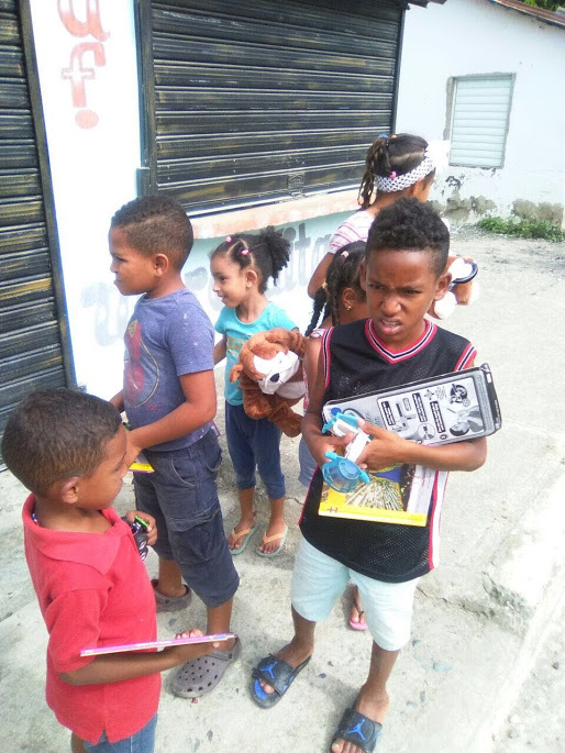 Children in line with their toys and books outside the school