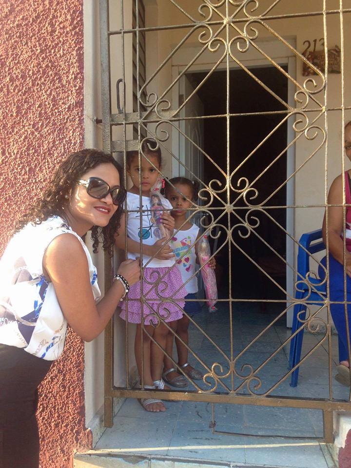 Our staff and two little girls inside a house with brown gate, holding their toys