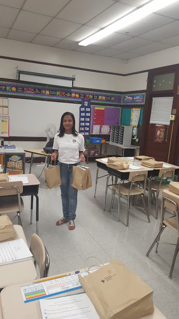 A woman in a classroom, holding paper bags