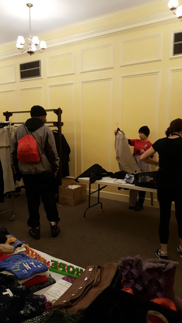A man standing and looking over the table with clothes while our female staff folds other clothes