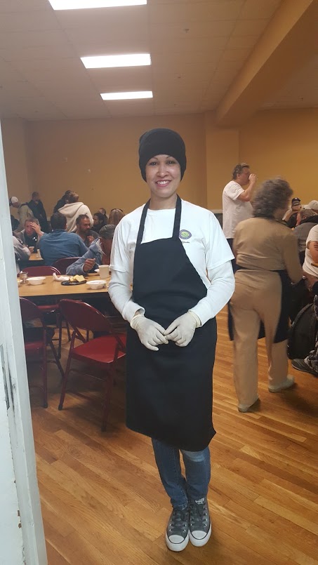 A female staff wearing a black bonnet and apron