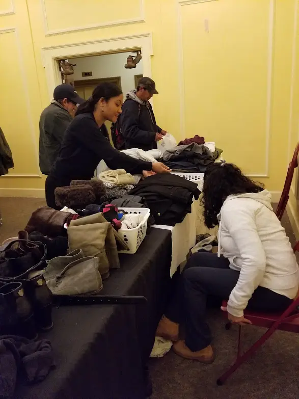 The table full of clothes and two of our female staff reaching for something