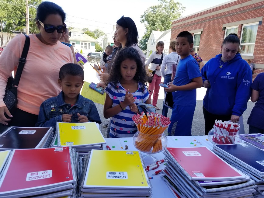 Parents and children looks through the notebooks and school supplies at our table