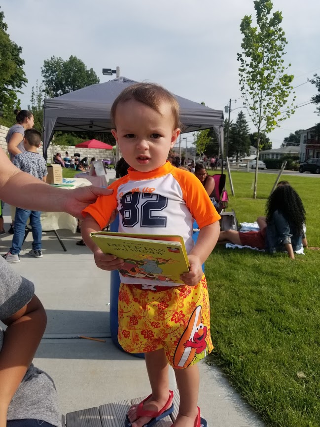 A baby wearing an orange and white shirt holding a book