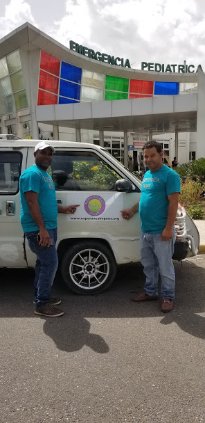 Two male staff in blue shirts pointing to the logo in our car