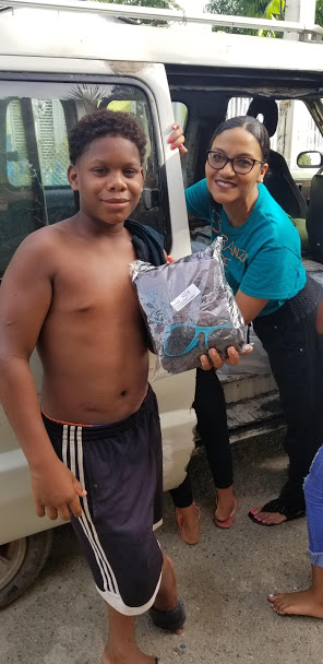 Our staff and a boy with no shirt, holding a pack of clothes
