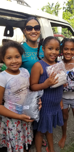 Our staff and three girls holding packs of clothes outside the car