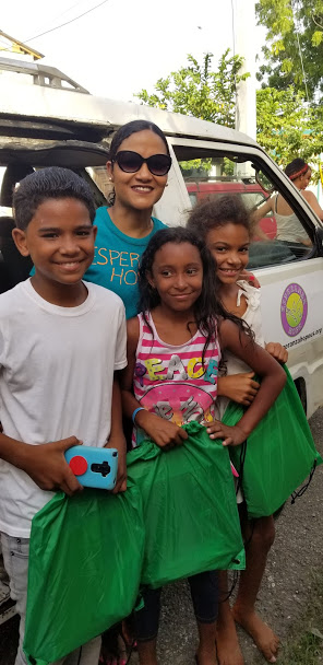 Our staff and three children smiling and each holding a green string bag