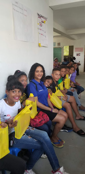 Our staff sitting with the older children with yellow tote bags at a long chair, 2