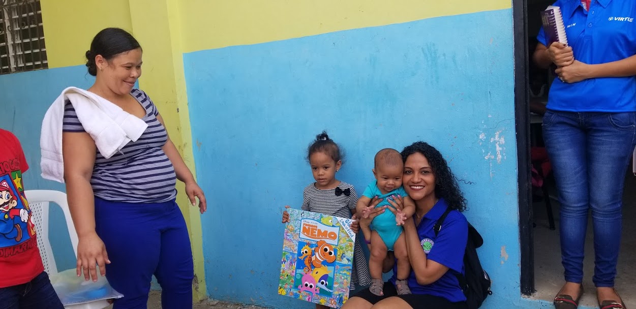 A little girl holding a Finding Nemo book and a staff carrying a baby and a woman smiling at them